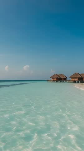 Vertical video showing overwater bungalows over turquoise lagoon and sandy shore tropical escape