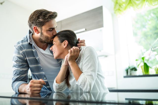 Man kissing on woman forehead at home