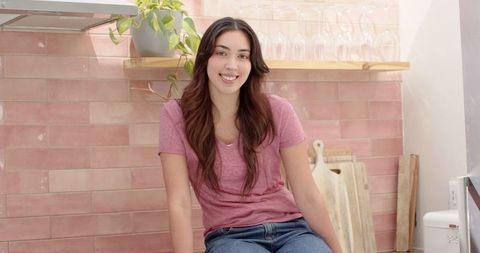 Woman Relaxing on Chick Pink Kitchen Counter in Modern Home