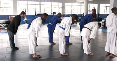 Diverse Male Classmates Bowing in Martial Arts Hall with Instructor