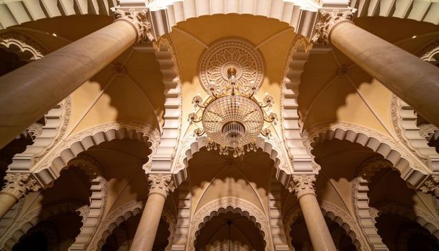 Glistening crystal chandelier hanging beneath ornate moorish arches and carved medallion