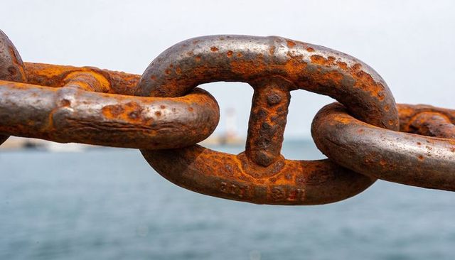 Rusted mooring chain link close-up showing heavy corrosion, weld marks and texture