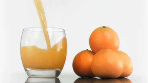 Fresh Tangerine Juice Pouring with Whole Tangerines on Side