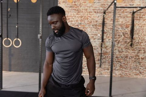 African american man resting after strength training in industrial gym with wooden rings