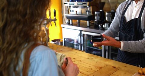 Barista Processing Contactless Payment at Cafe Counter
