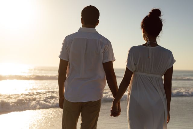 Rear view of couple standing together hand in hand on the beach