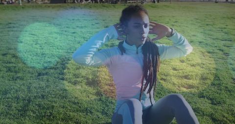 African American Woman Doing Abdominal Crunches on Grass in Sunlight