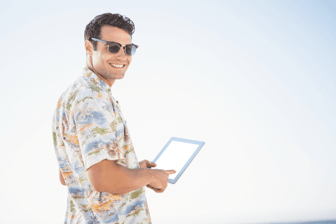 Man with Tablet in Sunglasses and Printed Shirt Against Clear Blue Sky