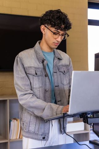 Young asian man working at standing desk using laptop in minimalist home office