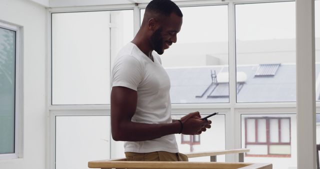 Smiling Man Texting on Smartphone in Modern Home - Download Free Stock Images Pikwizard.com