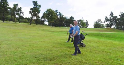 Father and son practicing golf swings on sunlit fairway