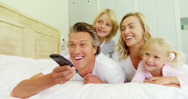 Happy Family Watching TV Together in Bedroom - Download Free Stock Images Pikwizard.com