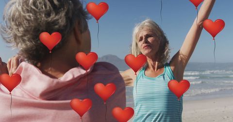 Senior Women Exercising on Beach with Heart Balloons