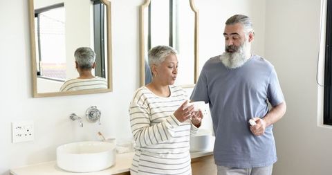 Senior couple discussing medication in modern bathroom