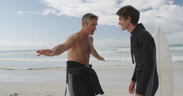 Father and son bonding while surfing at the beach creates memorable moments and strengthens their relationship. This can be used in family-focused advertisements, campaigns promoting outdoor activities, or any content that celebrates parental bonds and the joy of surfing.
