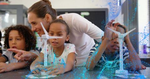 Teacher guiding kids with augmented reality wind turbine models for hands-on stem learning