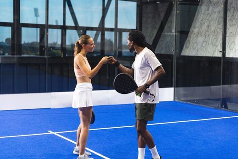 Diverse padel partners fist bumping on court