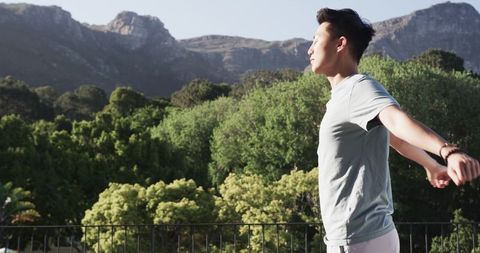 Man Enjoying Mountain Scenery from Balcony, Embracing Serenity