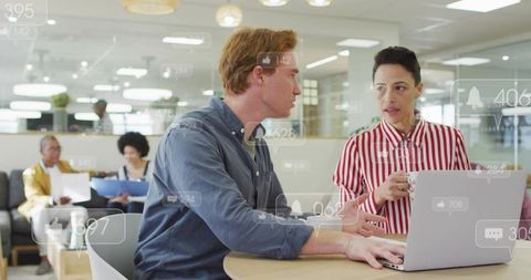 Collaborating over laptop in open-plan office with social media analytics overlays