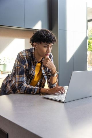 Man in Plaid Shirt Working on Laptop in Modern Kitchen Home Office