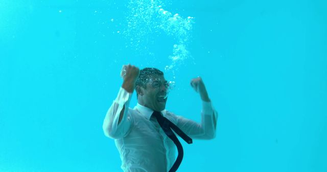 Businessman triumphing underwater in swimming pool