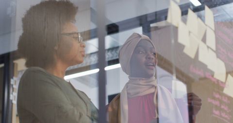 Two African American Businesswomen Brainstorming with Memo Notes in Office