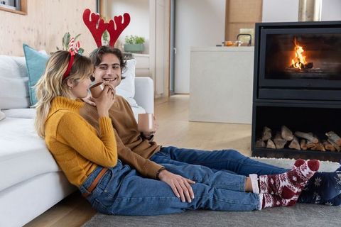 Happy couple relaxing by cozy winter fireplace in holiday attire