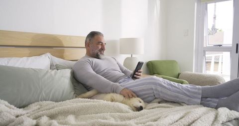 Mature Man Relaxing with Smartphone in Cozy Bedroom