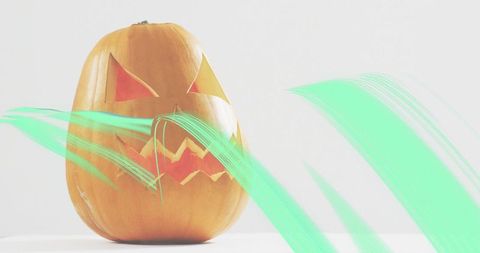 Glowing jack-o'-lantern emitting mint-green light streaks on minimal white surface
