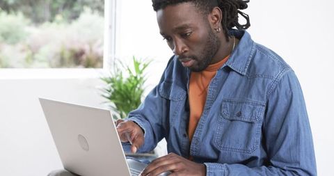 Focused African American Man Working Remotely on Laptop in Minimal Home Office Space