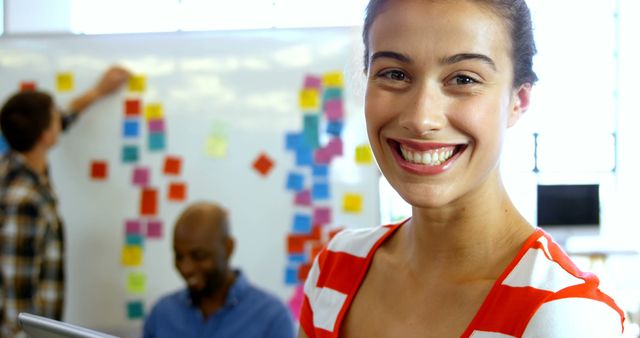 Smiling Professional Woman in Office with Colleagues and Sticky Notes - Download Free Stock Images Pikwizard.com