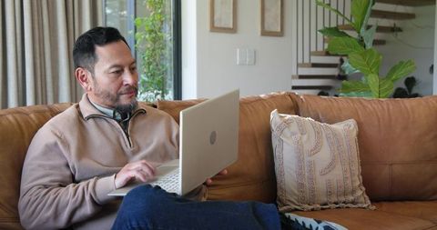 Asian Man Working on Laptop in Cozy Living Room Interior