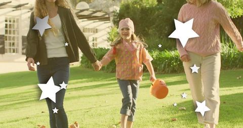 Multigenerational family walking holding child carrying pumpkin pail on sunny front lawn