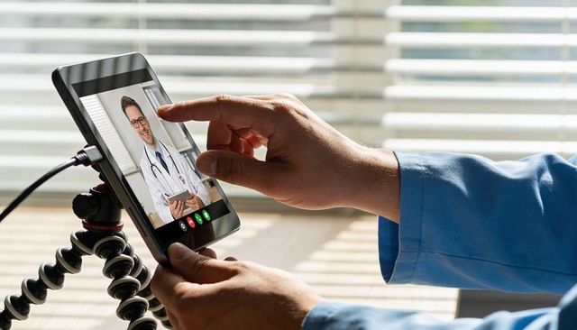 Patient tapping tablet for telemedicine video consult with remote doctor on screen