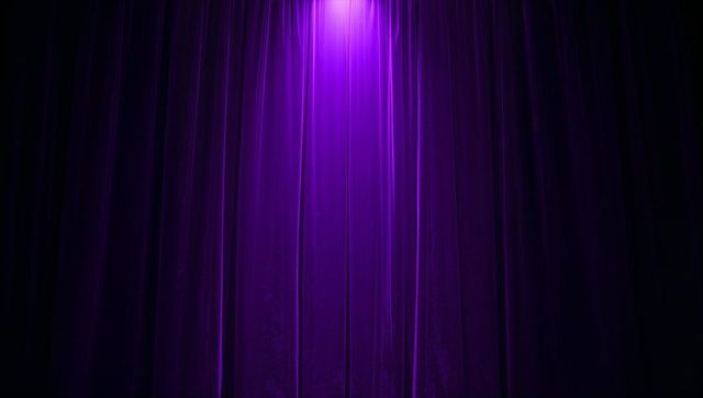 Purple velvet theater curtain under spotlight creating dramatic ambiance