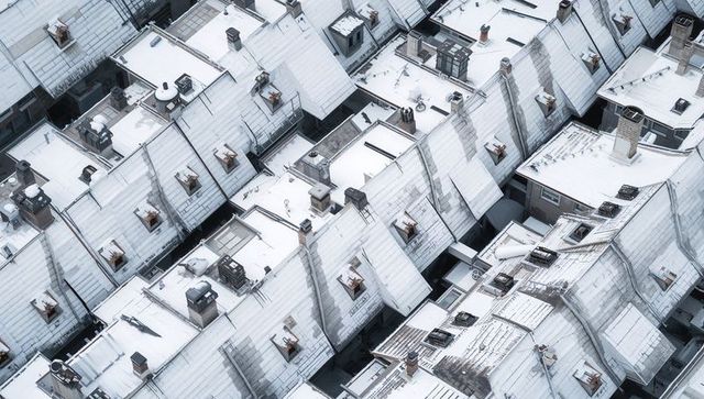 Aerial showcasing snow-covered pitched rooftops with chimneys, skylights and geometric pattern