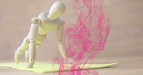 Balancing wooden mannequin performing diagonal crawl with pink powder plume on yellow pad