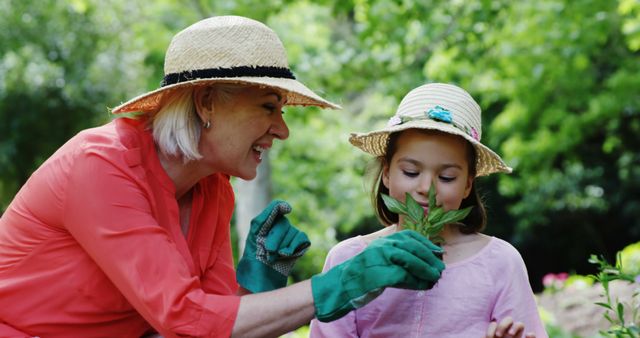 Woman and girl in sun hats enjoying gardening together in lush green garden, with vibrant plant. Perfect for content on outdoor activities, gardening, family bonding, environmental education, and sustainable living.