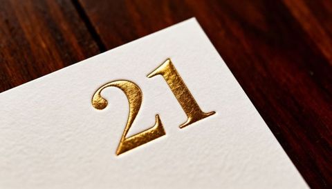 Elegant gold embossed 21 on white cardstock closeup featuring metallic foil for luxury invitations