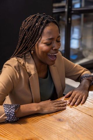 Joyful Businesswoman Laughing at Office Lounge Table