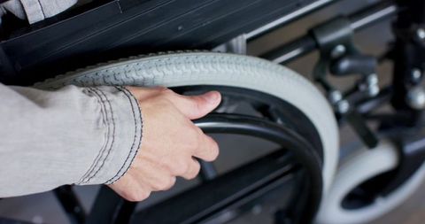 Man gripping wheelchair push rim showing independence and mobility closeup