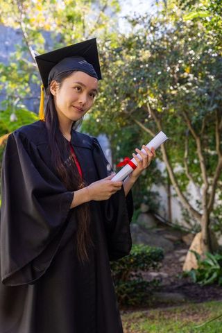 Graduate woman celebrates outdoors in academic attire