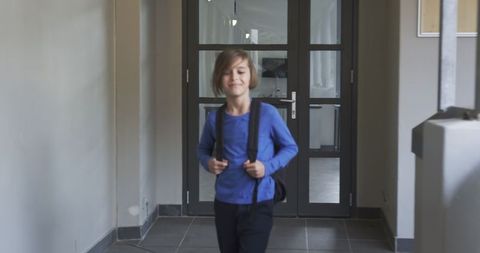 Preteen boy with backpack walking in modern hallway