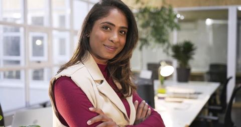 Confident asian businesswoman standing with arms crossed in modern office environment