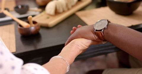 Senior Companions Hold Hands Over Meal Symbolizing Friendship
