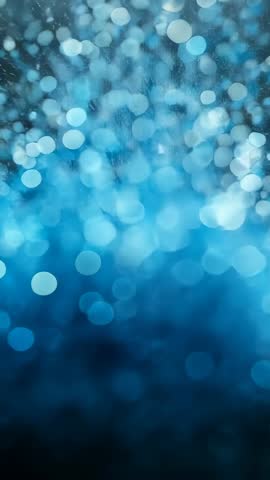 Pulling focus revealing cyan glitter dissolving into soft bokeh with shimmering particles