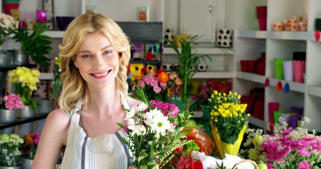 This image showcases a smiling female florist holding colorful flower bouquets in her vibrant shop, surrounded by various fresh flowers and plants. This can be used for promoting small businesses, florist services, or floral arrangement courses.