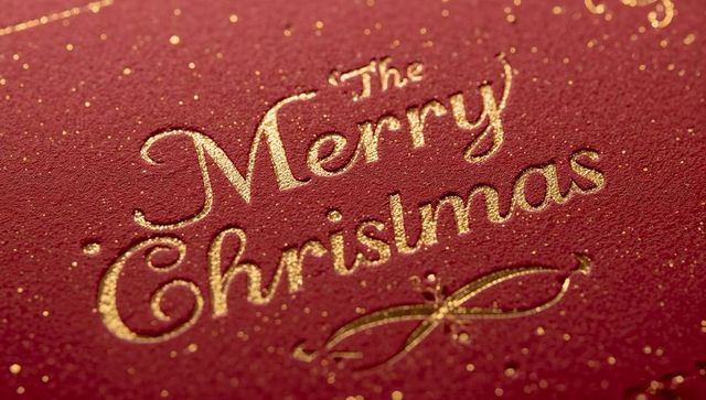 Merry Christmas Gold-Foil Embossed Card Shimmering on Red Textured Paper Closeup