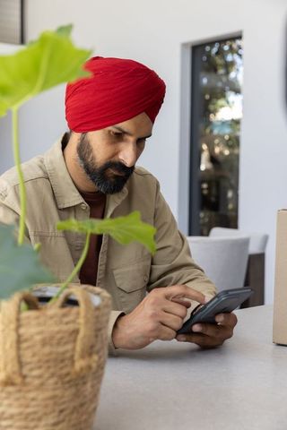 Indian man with red turban using smartphone at home