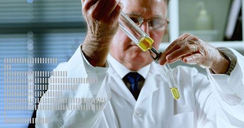 Senior scientist transferring yellow reagent with syringe into test tube at laboratory bench